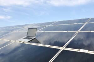 Laptop on photovoltaic solar panels against blue sky - - WoW Home