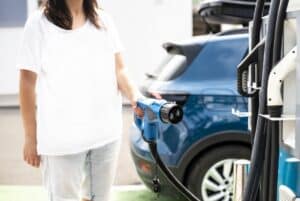 Woman charge Electric car on gas station. Blue car and electric - - WoW Home